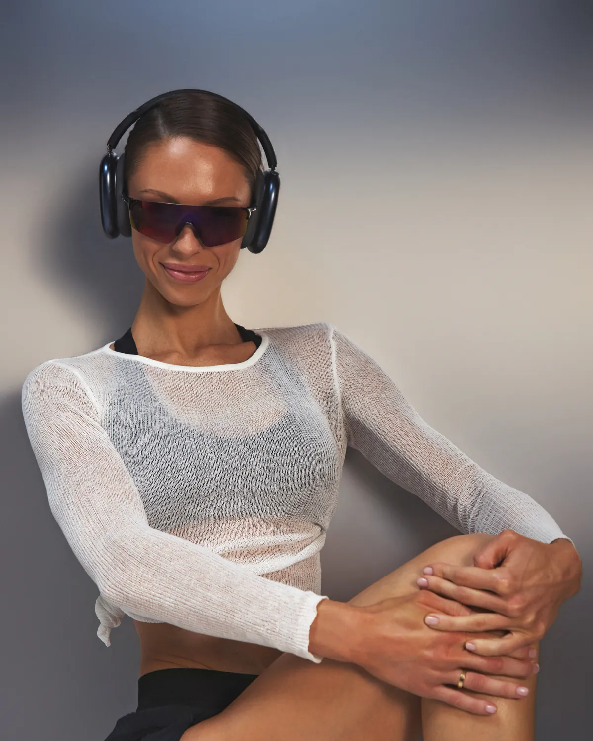 Jules smiling in a sheer white knit top